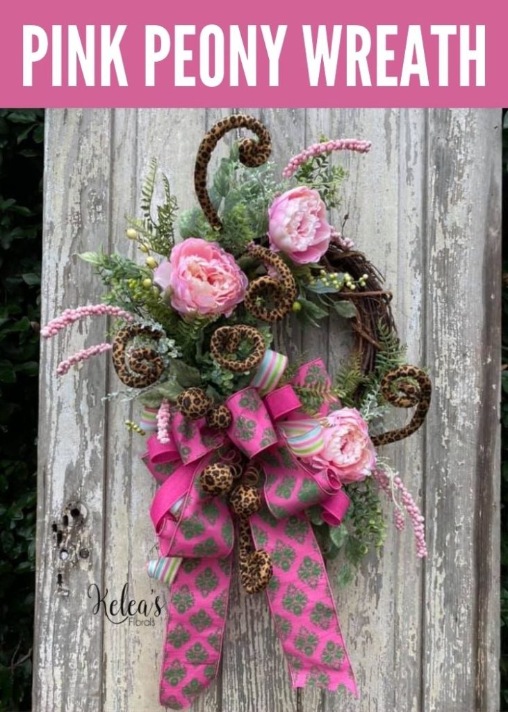 grapevine wreath with pink peonies hanging on a stressed door