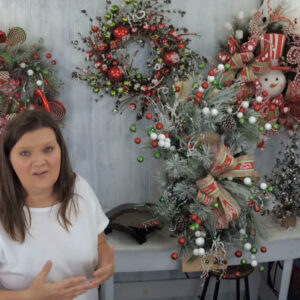 Kelea standing next to her large winter swag with ornaments, pinecones, and large bow