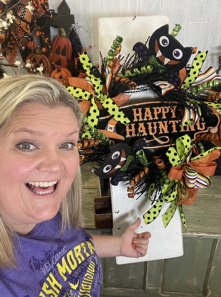 Kelea displaying a colorful Happy Haunting Halloween bat wreath