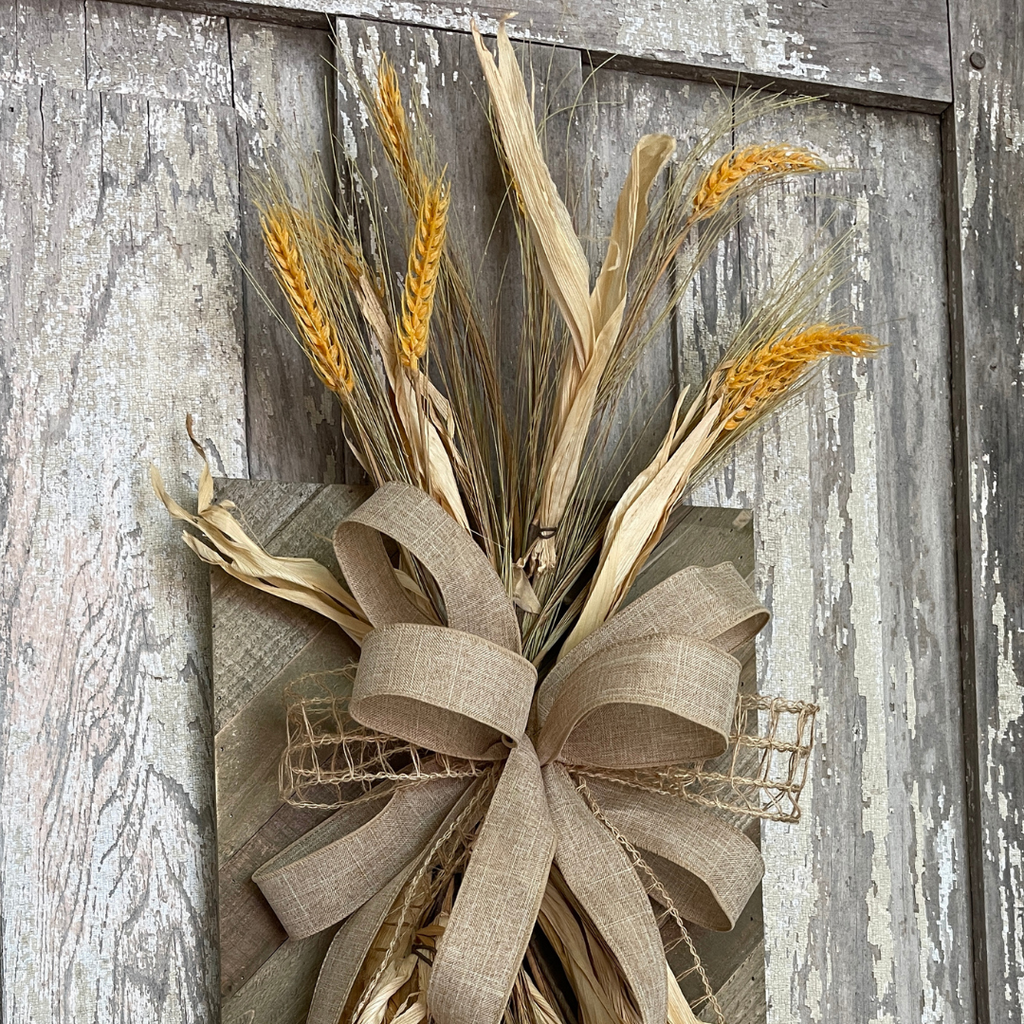 Wheat and corn husks extending above rustic fall wall decor
