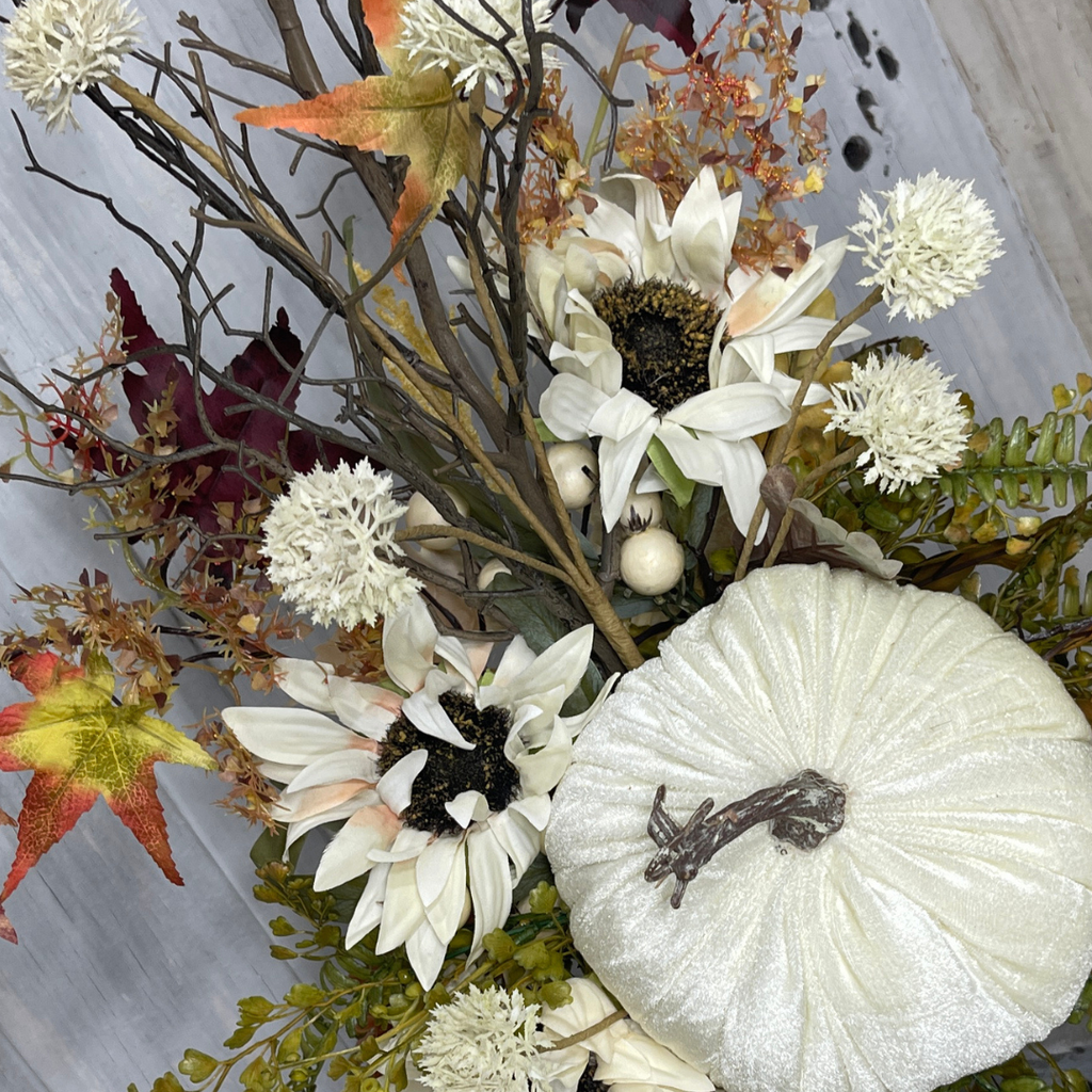 Sunflowers arranged around a velvet pumpkin in an elegant fall candlestick centerpiece