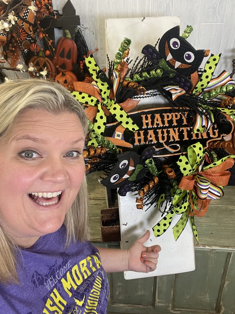 Kelea with colorful Halloween bat wreath with Happy Haunting sign