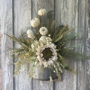 Neutral fall wall floral arrangement with cream pumpkins, sunflower and wispy greenery