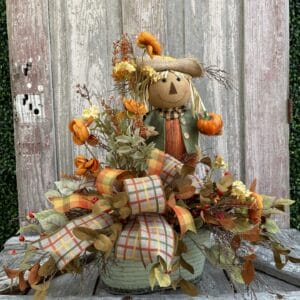 Scarecrow side table floral arrangement with autumn flowers, plaid ribbon and fall greenery
