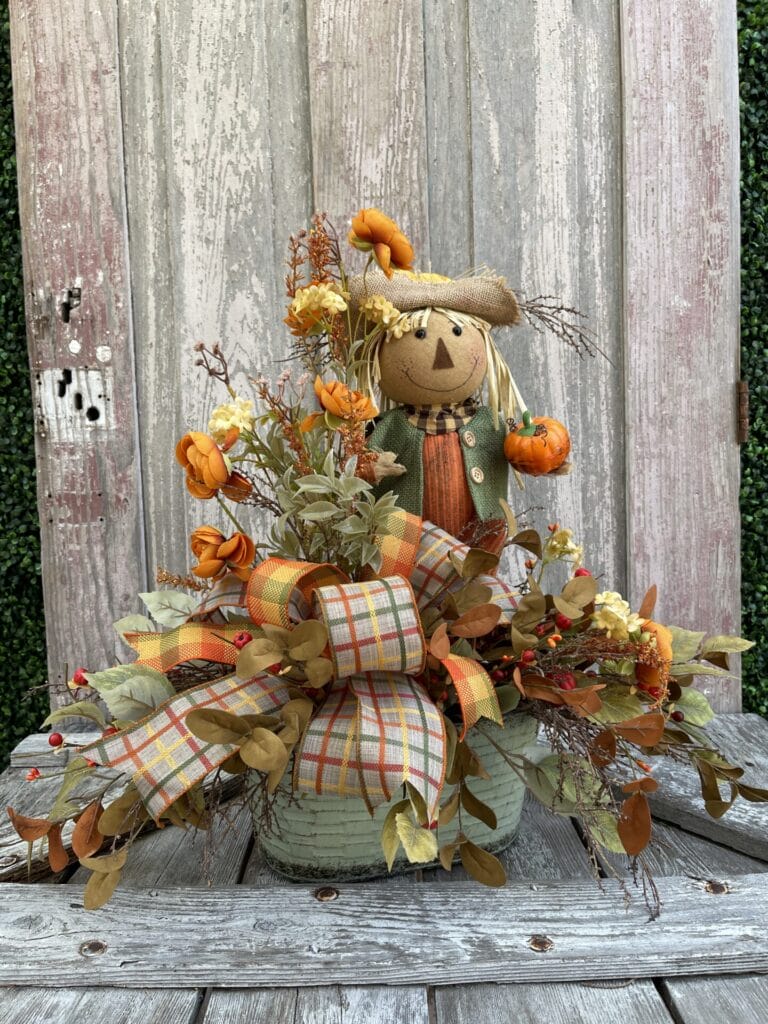 Scarecrow side table floral arrangement with autumn flowers, plaid ribbon and fall greenery