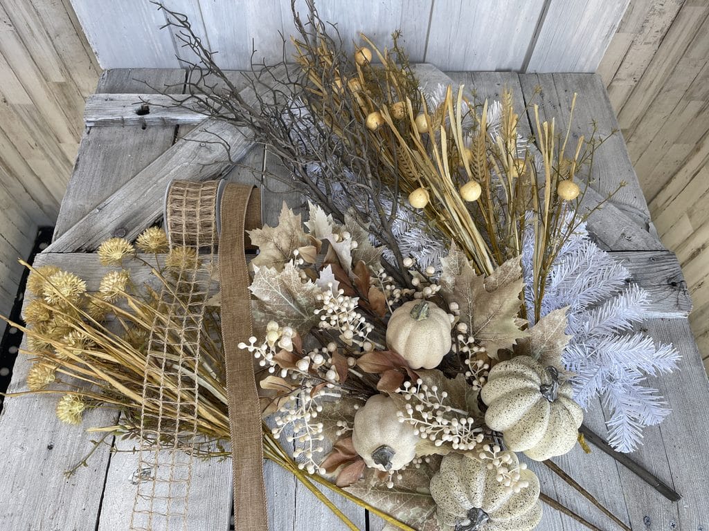 Supplies for a neutral pumpkin fall swag with wheat, berries, twigs and ribbon