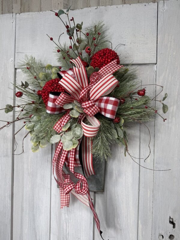 Christmas wall pocket floral arrangement with red and white ribbon winter greenery and berries